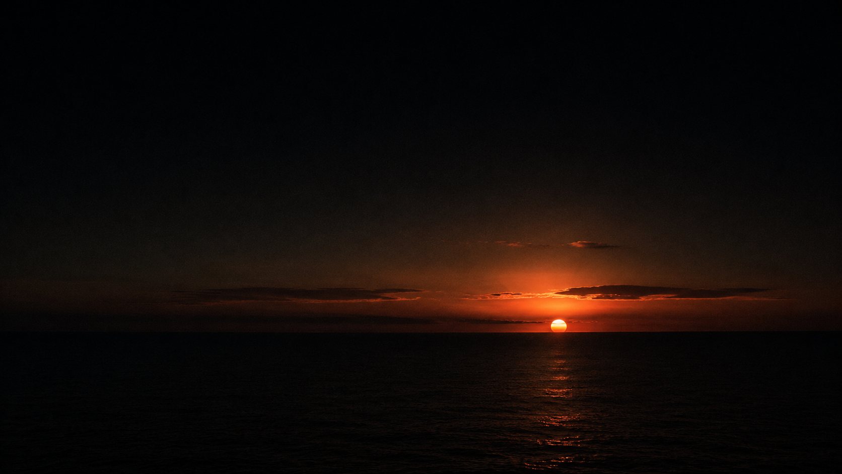 A coral sun setting over the ocean